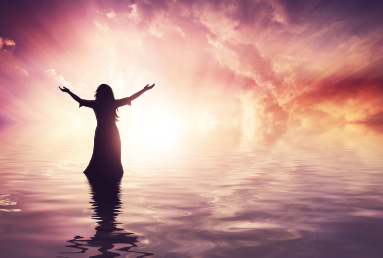womanliftingherhandsatsunset